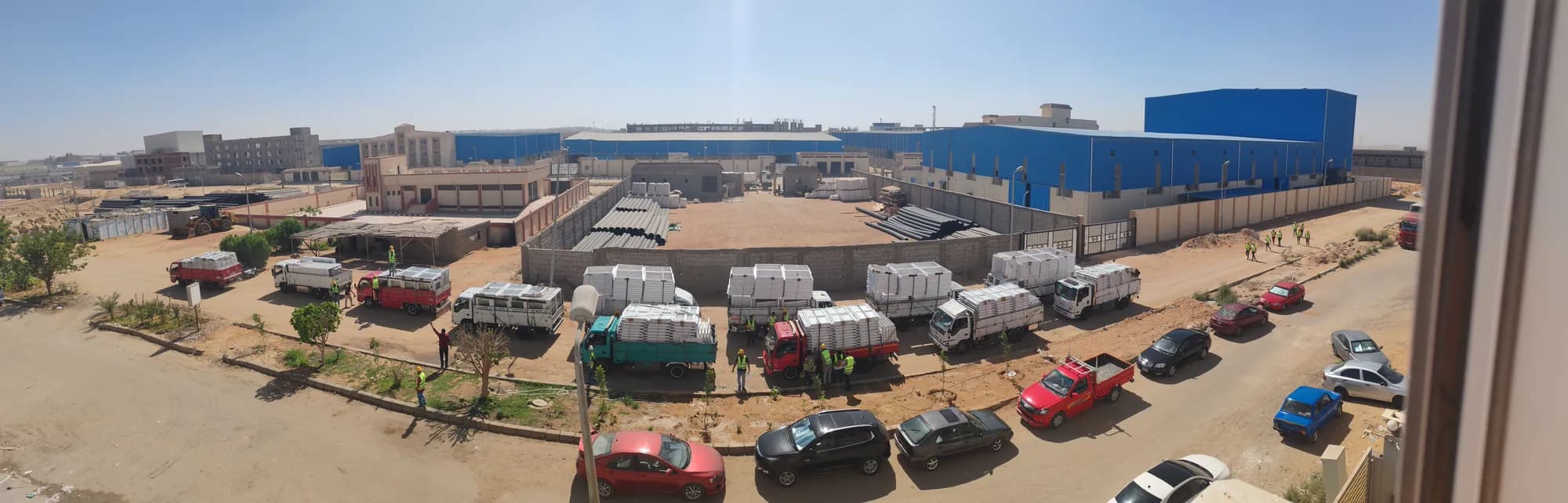 Convoy of flatbed trucks loaded with finished UPVC sashes outside the plant