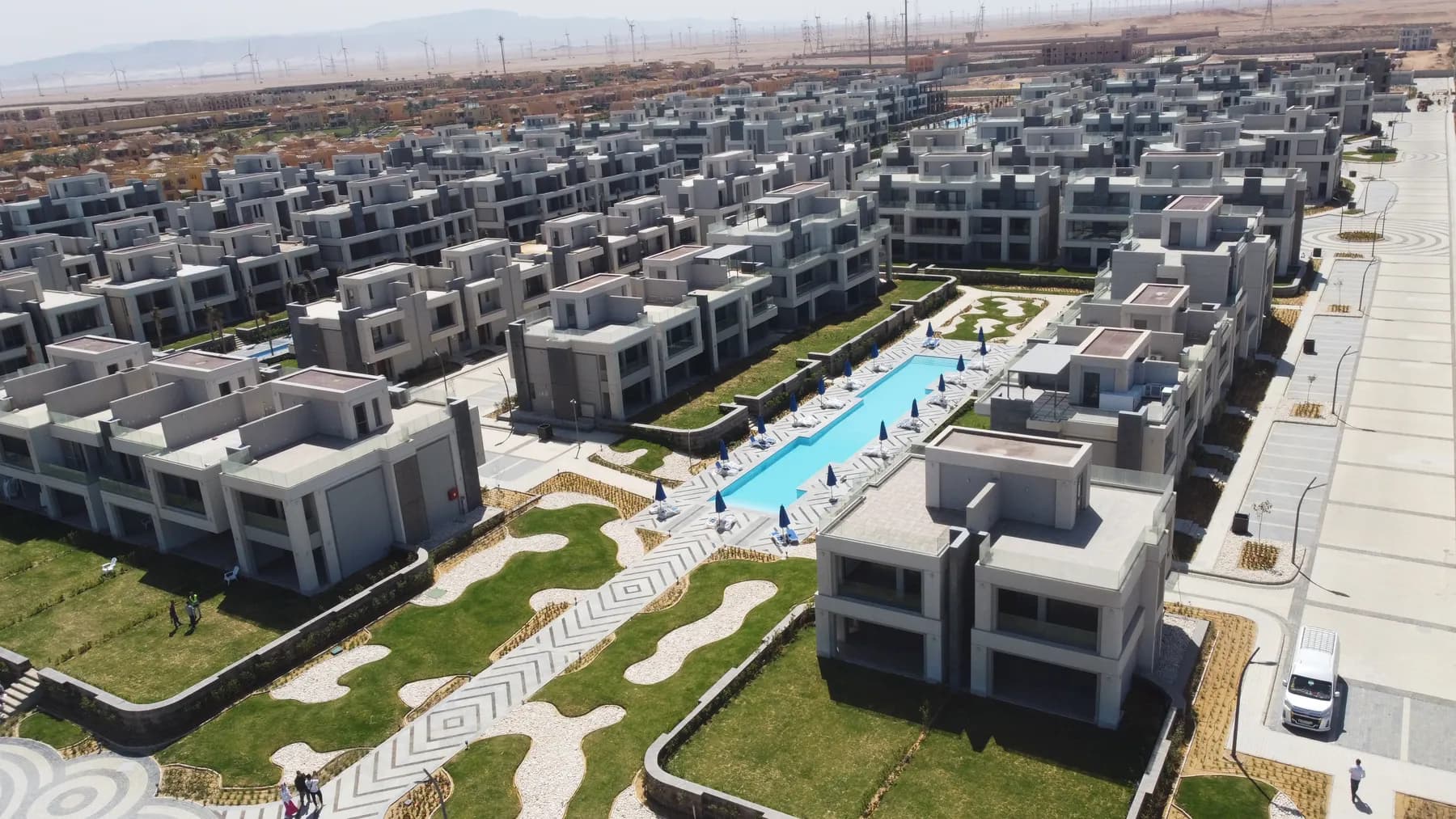 Aerial view of the finished seafront La Vista resort — landscaping, pools, and the sea beyond